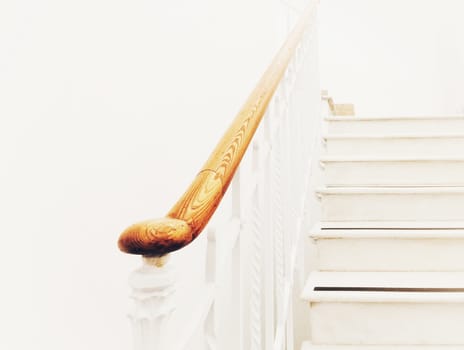 Ancient white staircase with elegant wooden handrail