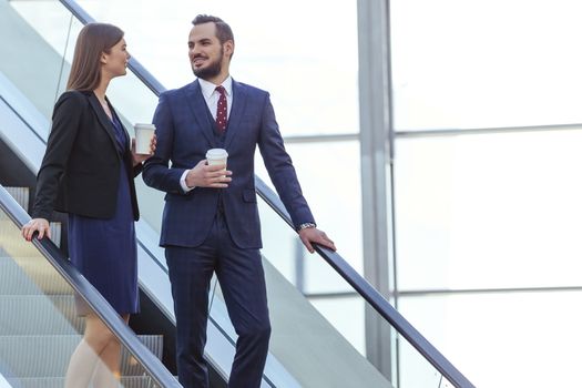 Business partners talking at escalator of business center