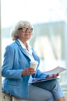 Senior business woman at coffee break with documents