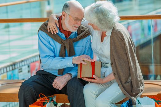 Senior couple in shopping mall with gifts