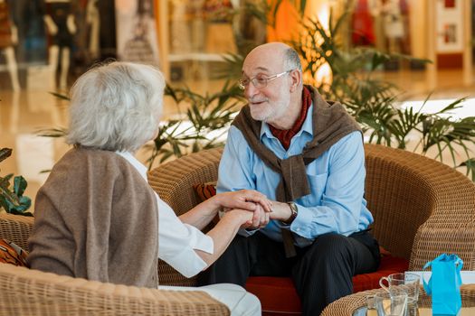 Romantic senior couple holding hands in cafe