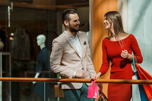 Happy beautiful young couple with shopping bags in mall