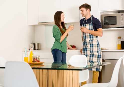 Young couple on the kitchen enjoying a  glass of white wine