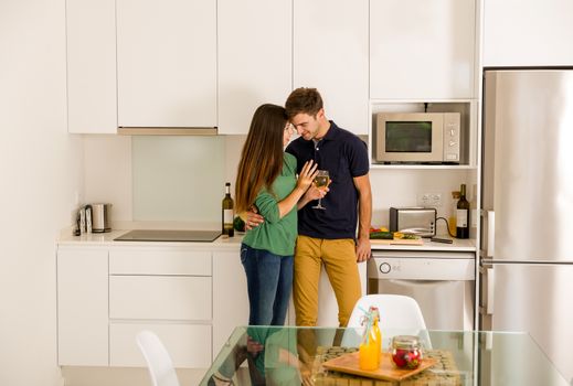 Young couple on the kitchen enjoying a  glass of white wine