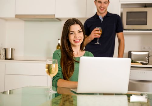 Young couple tasting wine and the women working on a laptop