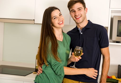 Young couple on the kitchen enjoying a  glass of white wine