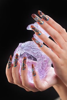 Woman's hand with nail art and glass on a black studio background