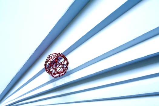 Red ball made from wire on paper staircase with outside shadow