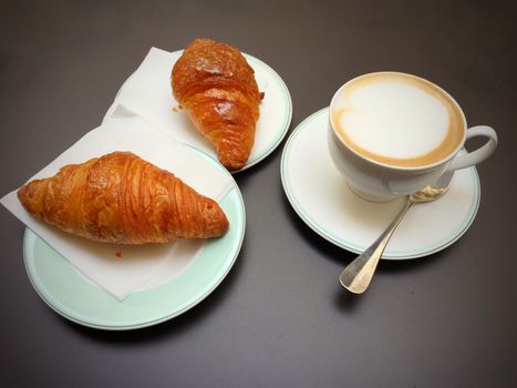 Cappuccino white cup, croissants on dark retro background, selective focus. Breakfast concept