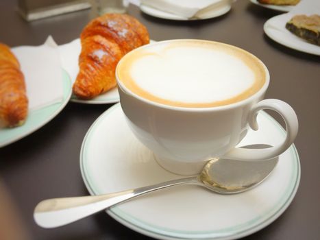 Cappuccino white cup, croissants on dark retro background, selective focus. Breakfast concept