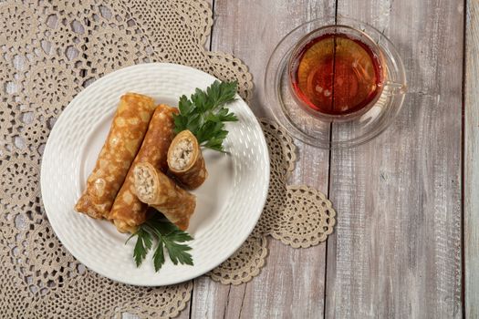 Plate with pancakes and a cup of tea on a wooden desk