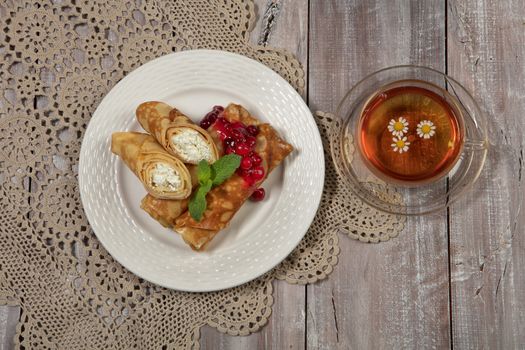 Plate with pancakes and a cup of tea on a wooden desk