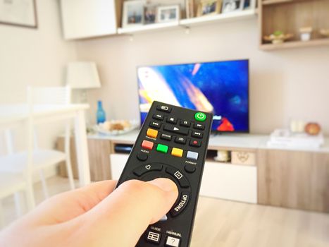 Male hand holding TV remote control. Point of view shot