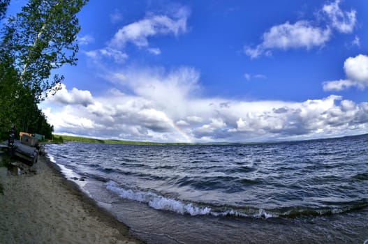 wave rages and runs on the shore of the lake on a bright Sunny day, shooting from the bottom point