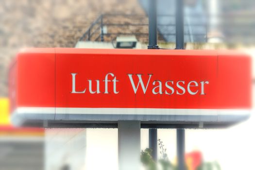 Red billboard with inscription in German "air and water" at a gas station.