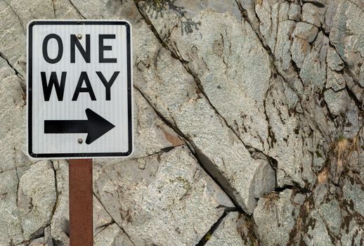 One Way highway road sign against grunge texture rock wall