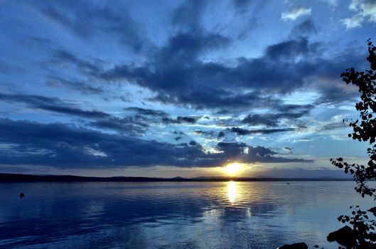the evening sky over the lake, silhouettes of clouds illuminated by the sun