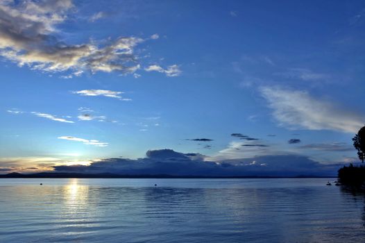 the evening sky over the lake, silhouettes of clouds illuminated by the sun