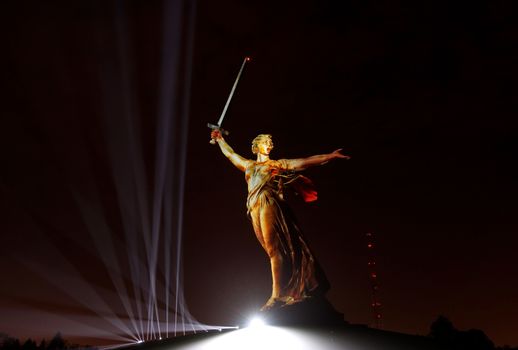 Sculpture the Motherland on Mamayev Kurgan in gold light during the show Light of the Great Victory 2018 of year                               