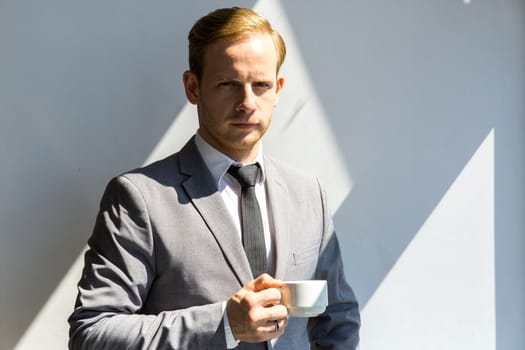 Portrait of serious business man holding a cup of coffee