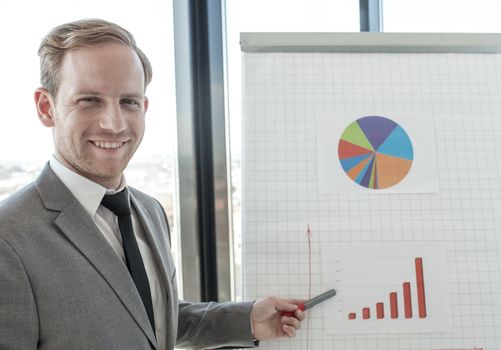 Business man making presentation of reports in diagrams and graphs at flip chart in offfice