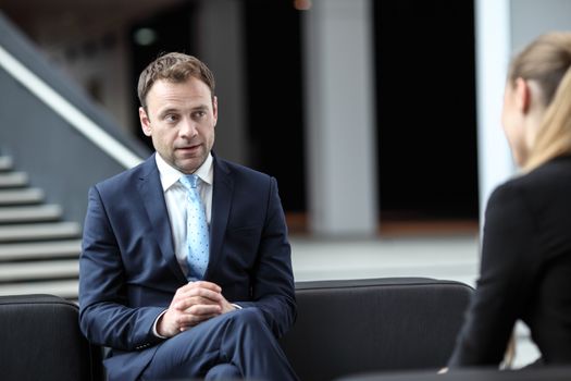 Business people talking sitting on sofa at office lobby, break, interview concept