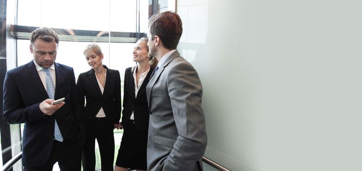 Business team group going on elevator. Business people in a large glass elevator in a modern office