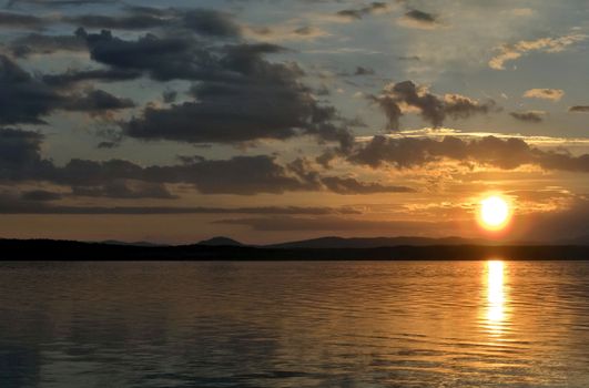 orange sunset over the lake, the sun lights up the clouds