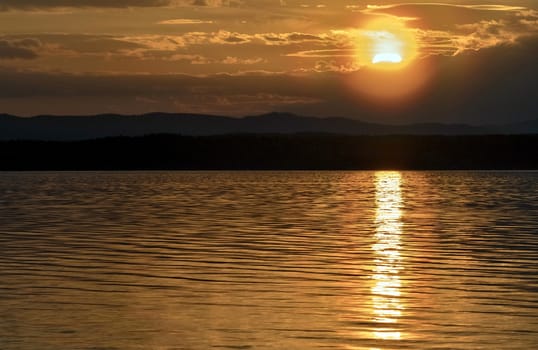 orange sunset over the lake, the sun lights up the clouds
