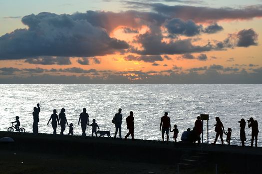 People silhouettes walking at sunset on the seaside