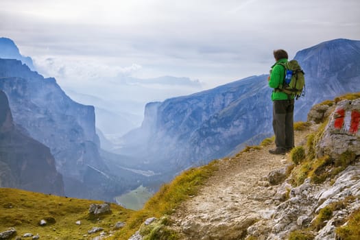 Young adventurer standing on a cliff in Dolomites, Italy