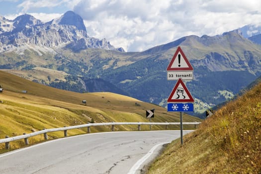 Warning road sign on a mountain road in Dolomites, Italy