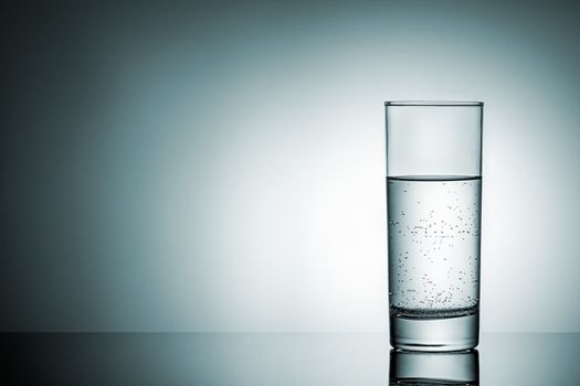 Glass of water with reflection. Background with gradient lighting.
