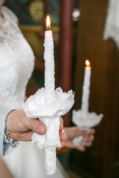 The groom and the bride hold candles in their hands