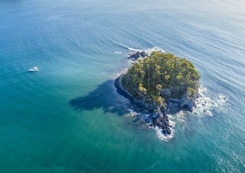 Aerial views of Snapper Island sitting 1 kilometre offshore in pristine aqua green waters of Batemans Bay Australia.  It lies a kilometre offshore and was a popular spot for smuggling as contraband could be hidden in the cave which had a back door escape route. Popular kayak or paddle venture.