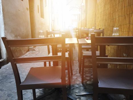 Chairs and tables of a restaurant with sunlight in backlight