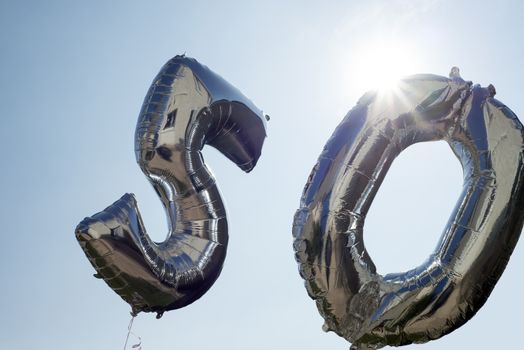 silver balloons for a 50th anniversary floating among the clouds