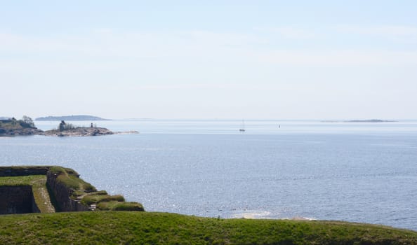 View from grassy hillside across Finnish waters from sea fortress Suomenlinna, Finland