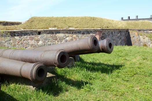 Four old abandoned military cannons on grass in a Suomenlinna bastion