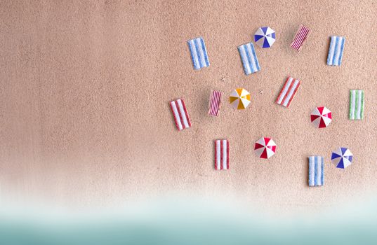 Miniature beach parasols and towels on sand 