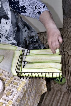 placing the cut zucchini on the grill, the hands of the cook are visible