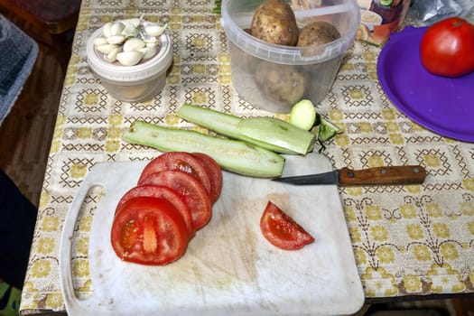 slicing tomatoes and zucchini on a cutting Board