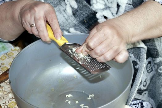 rubbing garlic on the grater, visible hands of the cook, cooking for the picnic