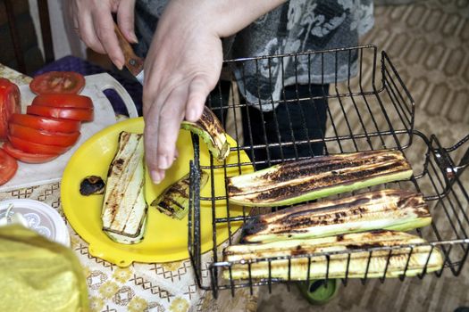 grilled zucchini spread on a plate, visible hands of the cook, cooking for the picnic