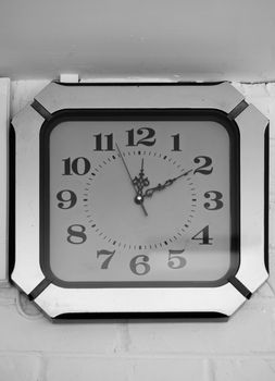 BLACK AND WHITE PHOTO OF ANTIQUE CLOCK MOUNTED ON WALL