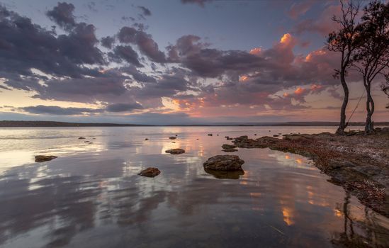 Tranquil sunset on the basin estuary with sunset reflections, the sound of gentle ripples and fish jumping