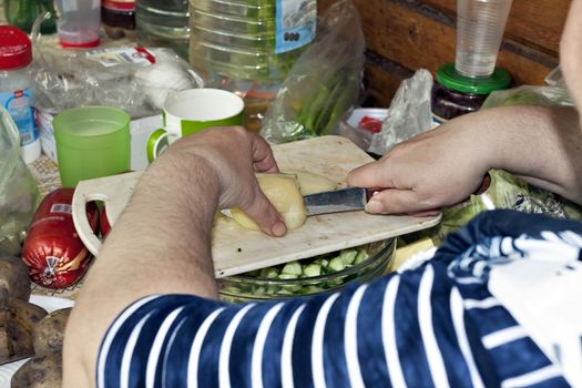 cleaning and cutting vegetables for salad, slicing boiled potatoes, visible hands of the chief
