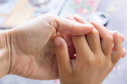 Two human hands of adult and child holding together showing love and careness