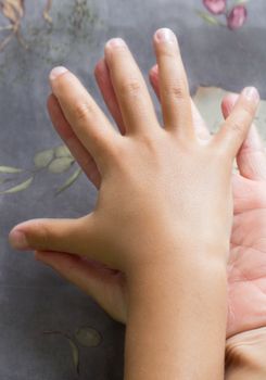 Two hands of adult and child hold together