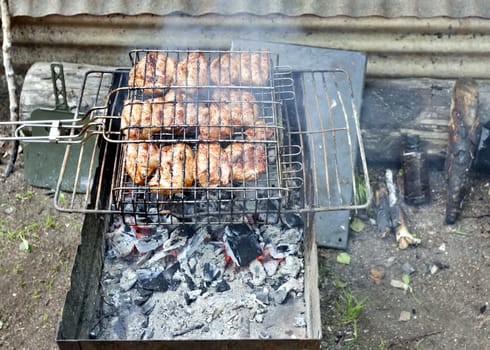 pieces of meat are grilled over hot coals, red coals visible